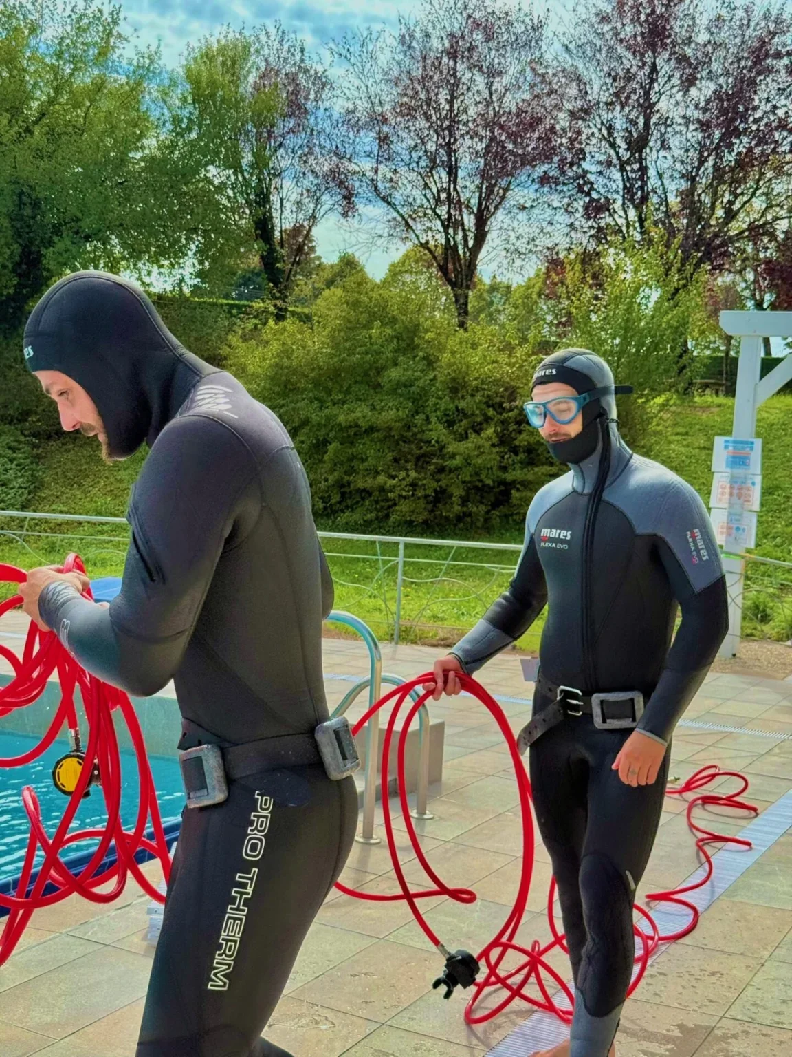 Zwei Fachkräfte in Tauchausrüstung bereiten die Leckortung am Pool vor