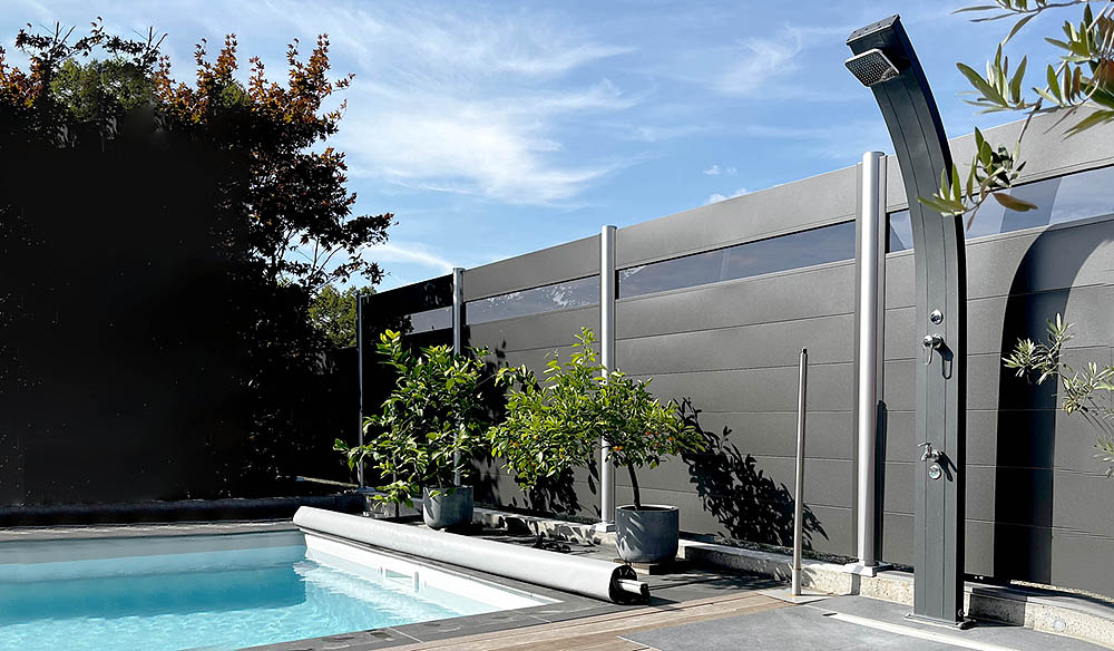 Eine schwarze Solardusche steht rechts vom Pool und dient als mögliches Zubehör