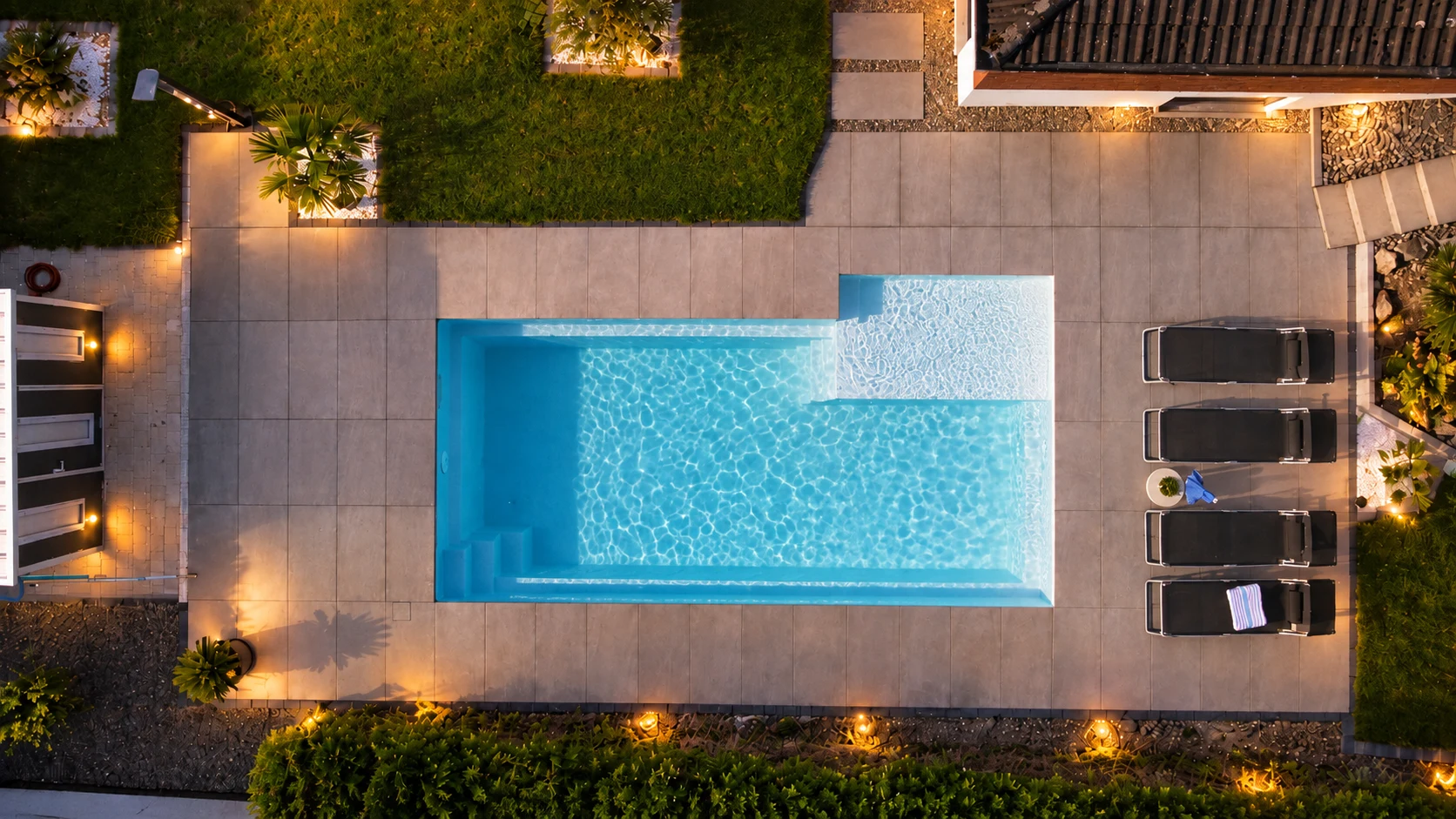 Pool und Gartenterrasse mit Abendbeleuchtung aus der Vogelperspektive